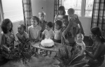 Birthday party for Khodadad Ardjomandi, Soekie Ardjomandi left, Carrie, Roger Veira holding baby, probably in home of John and Ann Veira, Paramaribo (1/76)