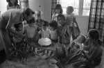 Birthday party for Khodadad Ardjomandi, Soekie Ardjomandi left, Carrie, Roger Veira holding baby, probably in home of John and Ann Veira, Paramaribo (1/76)