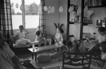 Lygia Vasilda on the couch with Dawn, Carrie and baby, Eddie Cruz far left with camera, birthday party for Khodadad Ardjomandi, probably in home of John and Ann Veira, Paramaribo (1/76)