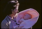 Joyce w baby Arthur swaddled in blanket in patio, 10/12/1942