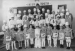 Emi w/ first grade classmates as alphabet, front center, c. 1969